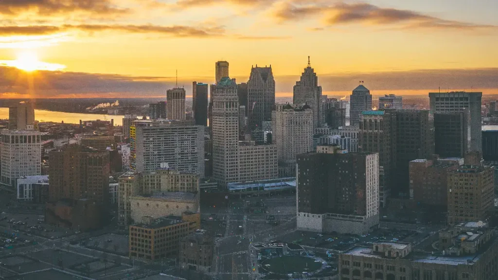Aerial view of Detroit skyline at sunrise, showcasing the city's silhouette against a vibrant morning sky