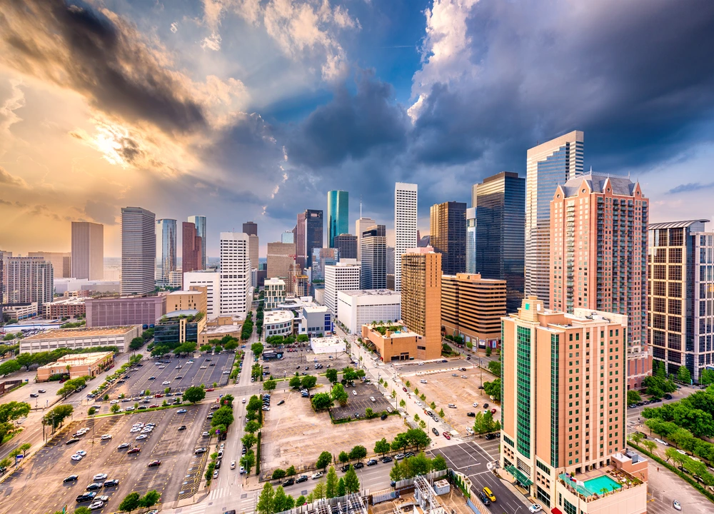 Houston skyline at sunset, showcasing tall buildings against a vibrant orange and purple sky