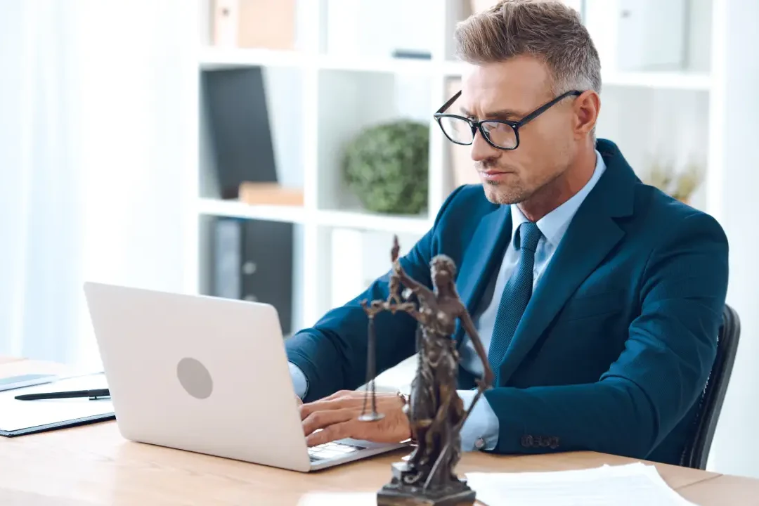 A man in a suit focused on his laptop, engaged in professional work | asbestos lawyer