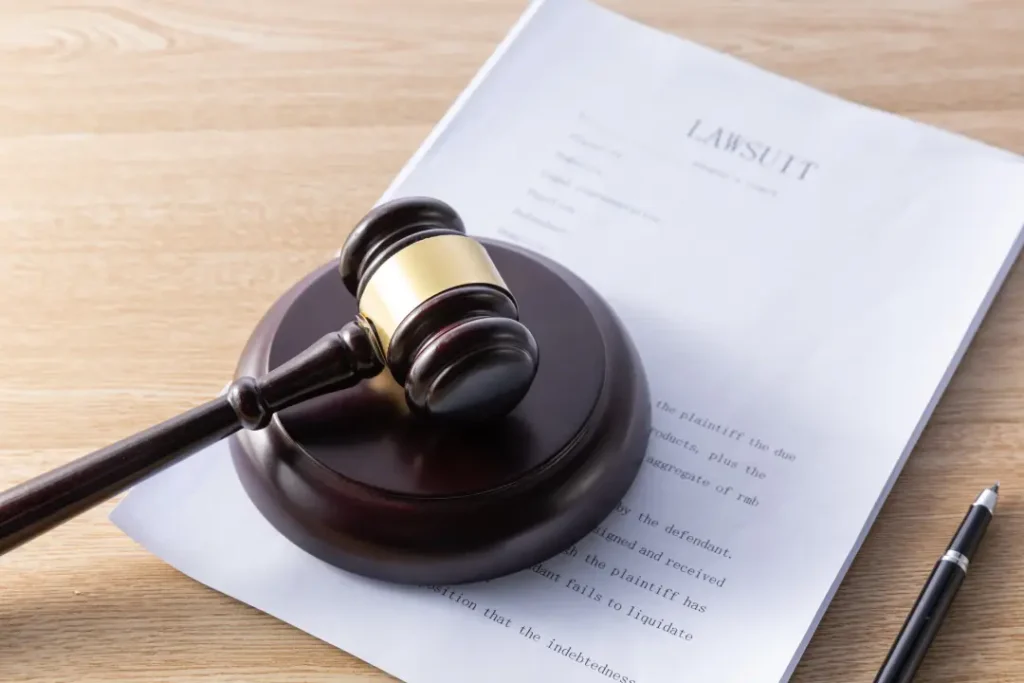 A judge's gavel and pen rest on paper on a polished wooden table.