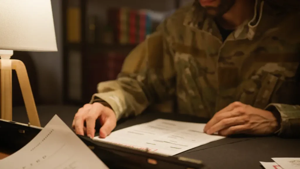 A soldier reviews veteran claims paperwork at a desk