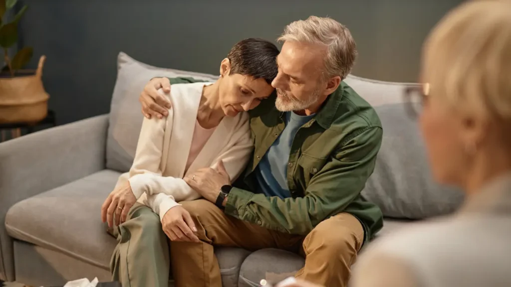 Elderly couple sitting together, looking worried, symbolizing the emotional burden of a mesothelioma compensation claim.