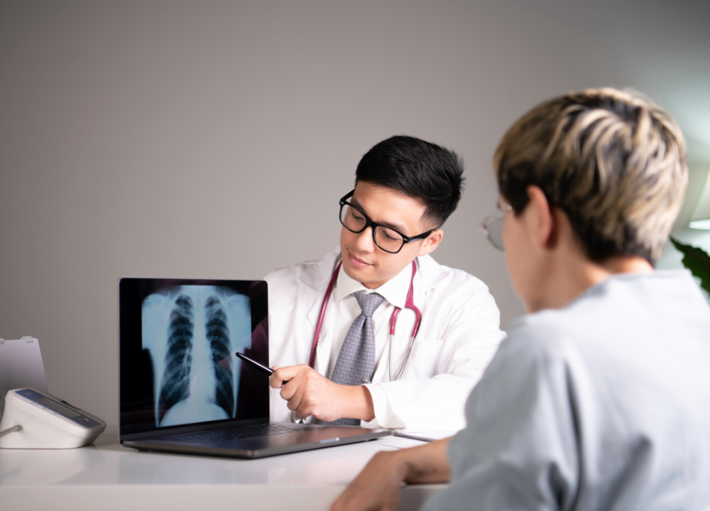 A worker meeting with a doctor while reviewing a lung X-ray.