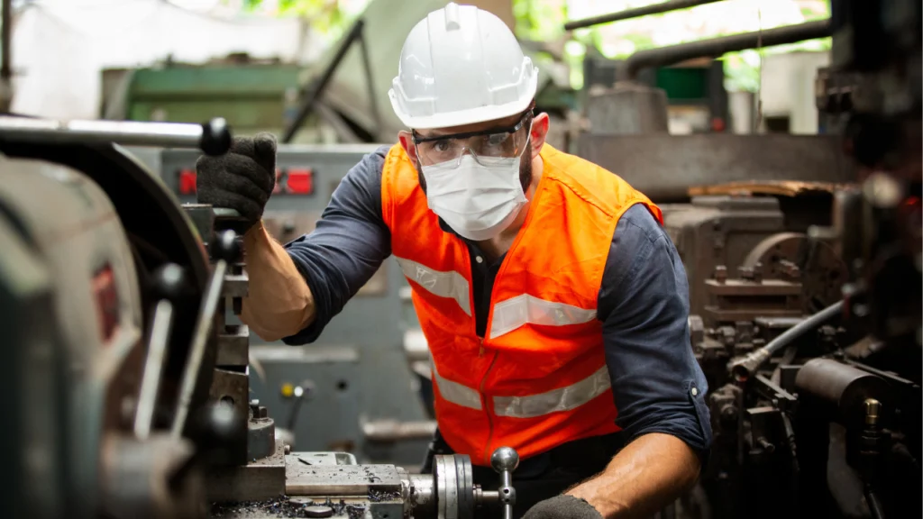 Man in PPE holding steel and metals in an industrial setting.
