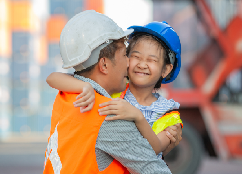 Man hugging his daughter in a shipyard after work.