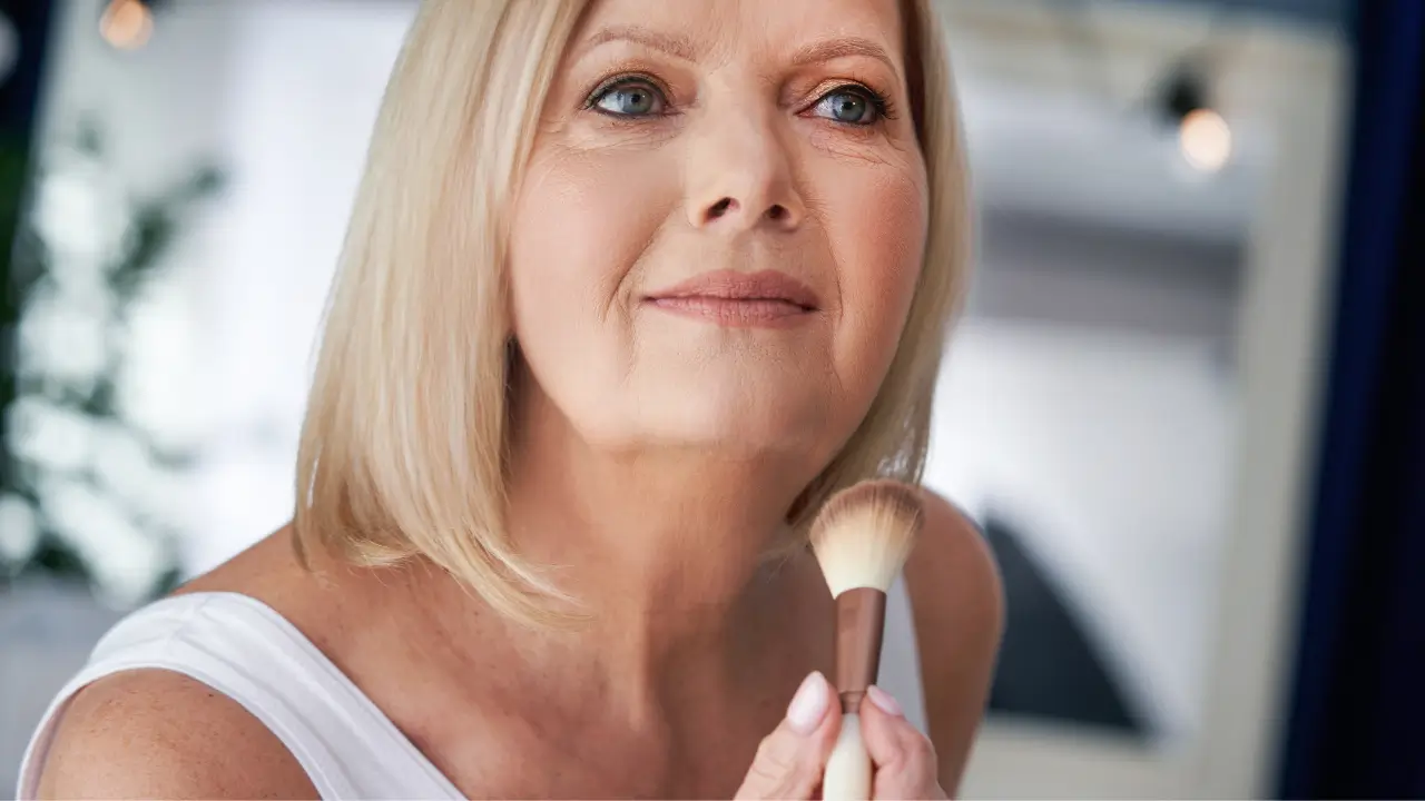 senior woman applying makeup with a powder brush