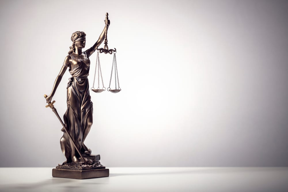 Lady Justice statue holding scales and sword, wearing a blindfold to symbolize fairness and impartiality