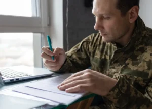 Veteran completing paperwork and filling out a VA claim form for mesothelioma benefits, highlighting the claim process for veterans and families.